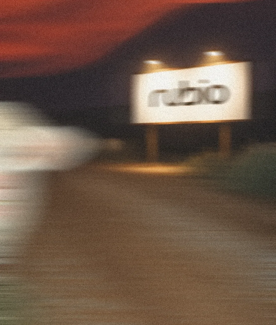 A Rubio billboard by a road at dusk, seen from a passing car
